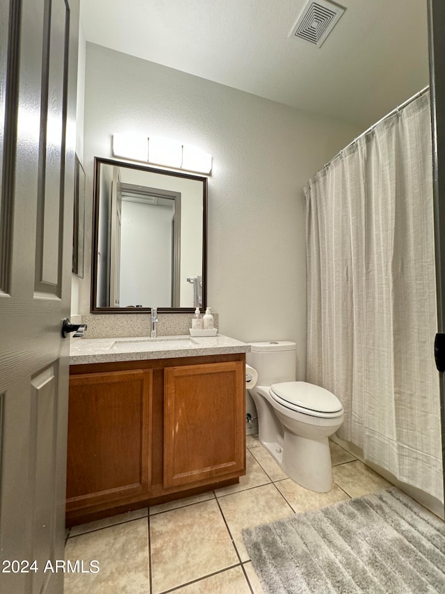 bathroom with toilet, vanity, and tile patterned floors