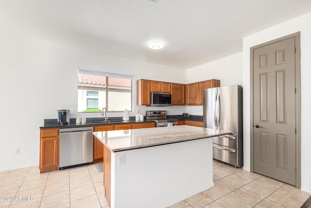 kitchen with light tile patterned floors, sink, appliances with stainless steel finishes, and a center island