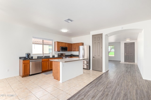 kitchen with appliances with stainless steel finishes, light hardwood / wood-style floors, and a center island