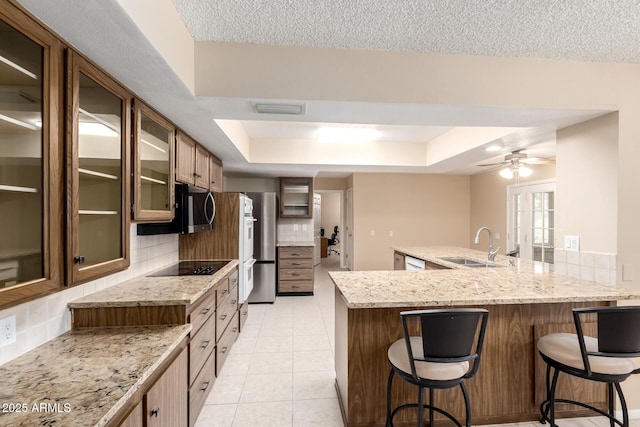 10126 W Sombrero Cir, Sun City, AZ 85373 - kitchen featuring a raised ceiling, freestanding refrigerator, decorative backsplash, a breakfast bar area, and a sink