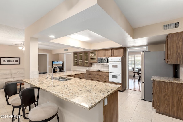 10126 W Sombrero Cir, Sun City, AZ 85373 - kitchen featuring a sink, a peninsula, a breakfast bar area, appliances with stainless steel finishes, and light tile patterned floors