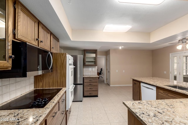 10126 W Sombrero Cir, Sun City, AZ 85373 - kitchen with black electric cooktop, decorative backsplash, baseboards, white dishwasher, and a raised ceiling