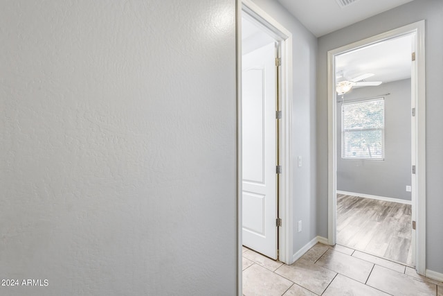 hallway featuring light tile patterned floors and baseboards