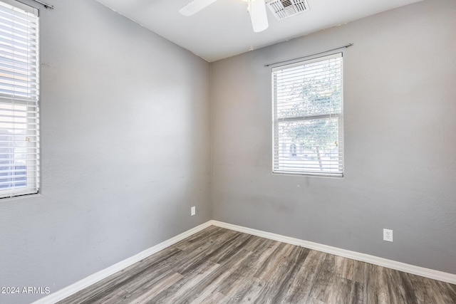 empty room with a ceiling fan, baseboards, visible vents, and wood finished floors