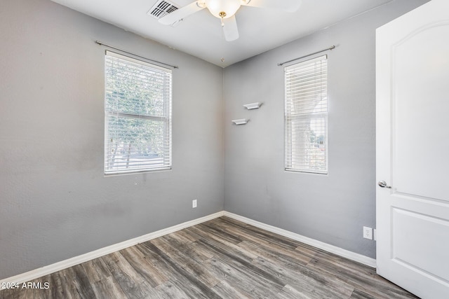 empty room featuring visible vents, baseboards, dark wood finished floors, and a ceiling fan