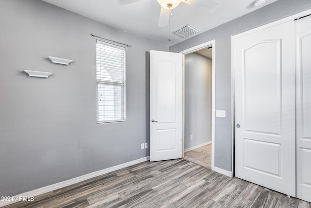 unfurnished bedroom featuring baseboards, visible vents, ceiling fan, light wood-style floors, and a closet