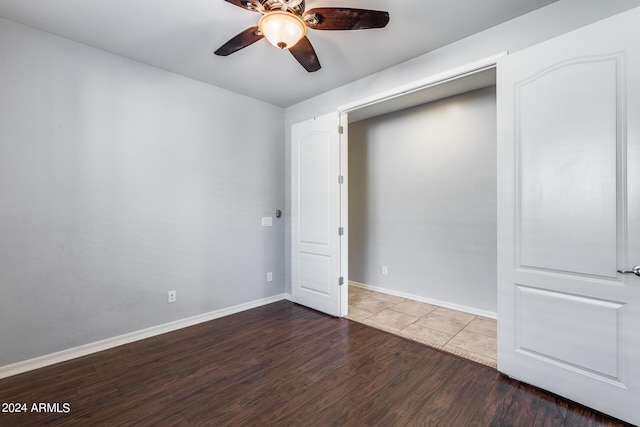 empty room featuring dark wood finished floors, baseboards, and ceiling fan