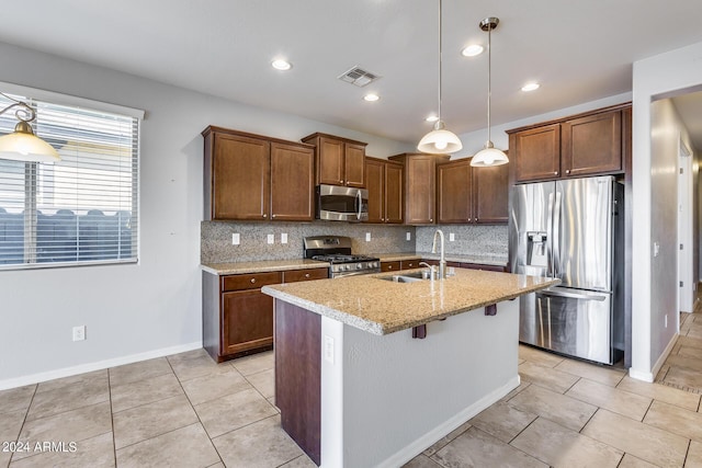 kitchen with visible vents, appliances with stainless steel finishes, a sink, an island with sink, and light stone countertops