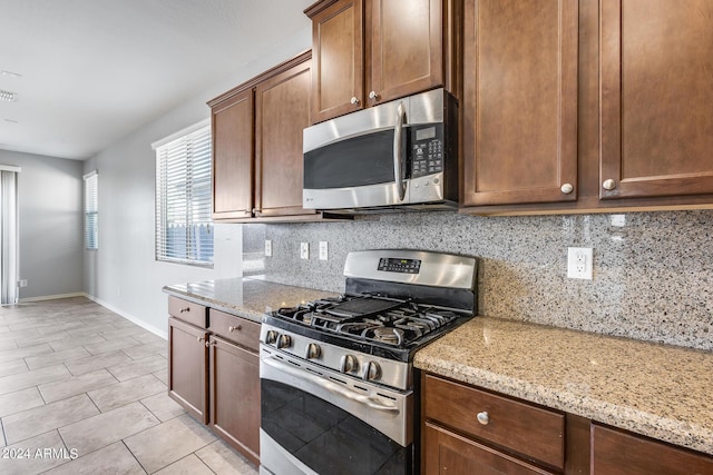 kitchen featuring appliances with stainless steel finishes, tasteful backsplash, baseboards, and light stone countertops