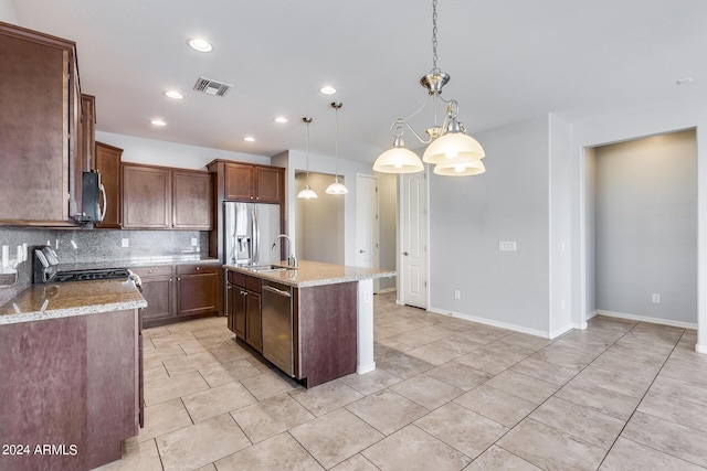 kitchen with a center island with sink, decorative backsplash, appliances with stainless steel finishes, decorative light fixtures, and a sink