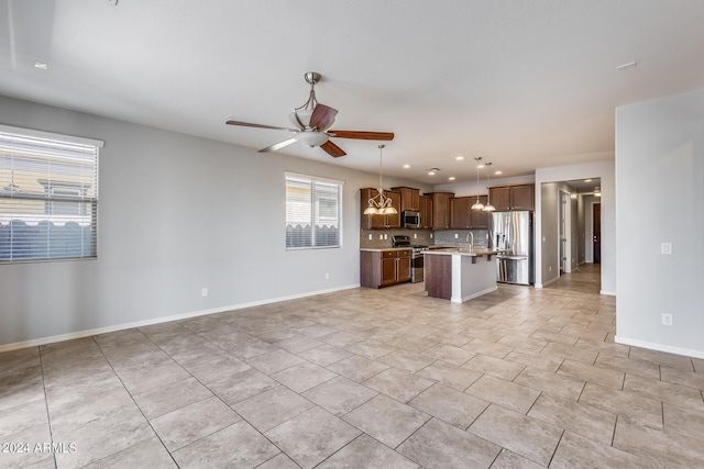 kitchen featuring stainless steel appliances, a kitchen island, open floor plan, hanging light fixtures, and brown cabinets