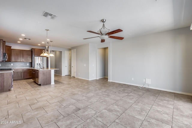 kitchen featuring a center island with sink, light countertops, visible vents, brown cabinetry, and open floor plan