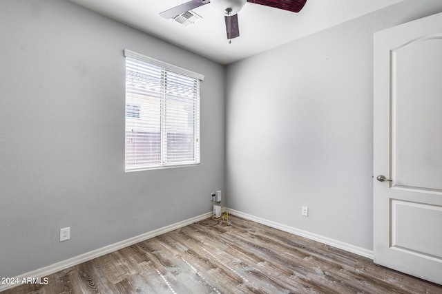 empty room with ceiling fan, visible vents, baseboards, and wood finished floors