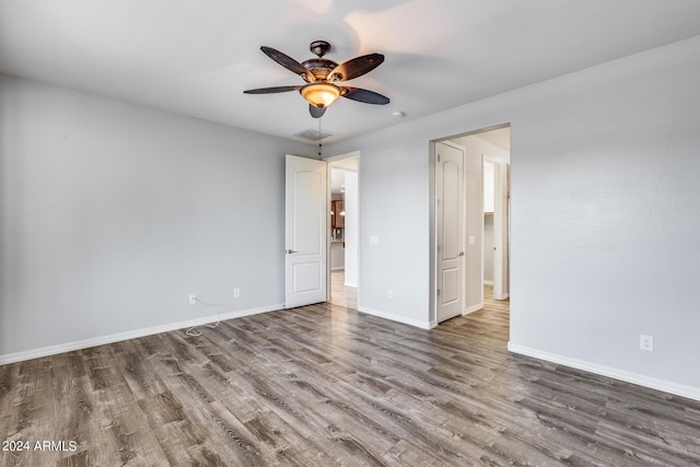 unfurnished room with visible vents, wood finished floors, a ceiling fan, and baseboards