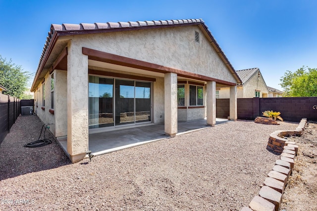 rear view of property featuring a fenced backyard, a patio, central AC, and stucco siding