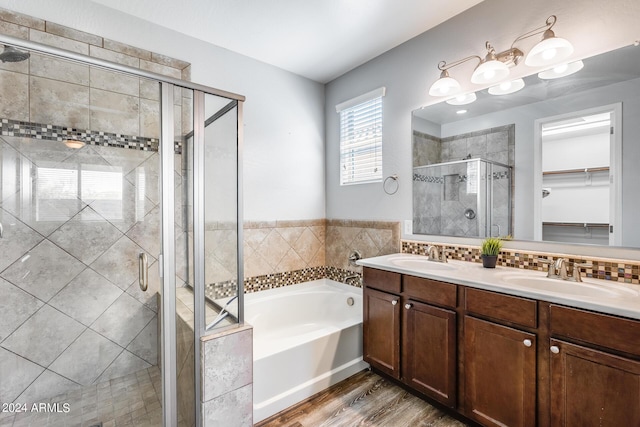 full bathroom featuring a stall shower, a walk in closet, a sink, and a bath