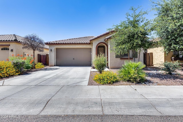 mediterranean / spanish house featuring an attached garage, a tiled roof, concrete driveway, and stucco siding