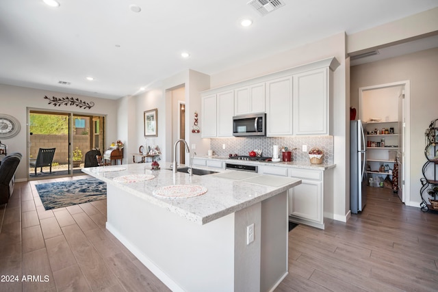 kitchen with appliances with stainless steel finishes, an island with sink, sink, and white cabinets