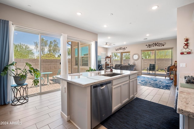 kitchen featuring light hardwood / wood-style floors, ceiling fan, a center island with sink, and stainless steel dishwasher