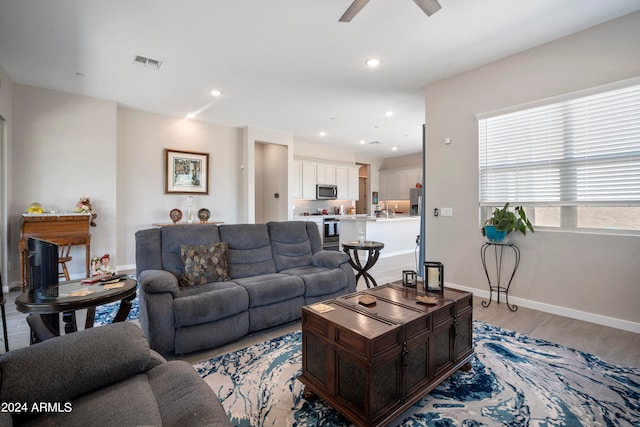 living room featuring ceiling fan and light hardwood / wood-style floors