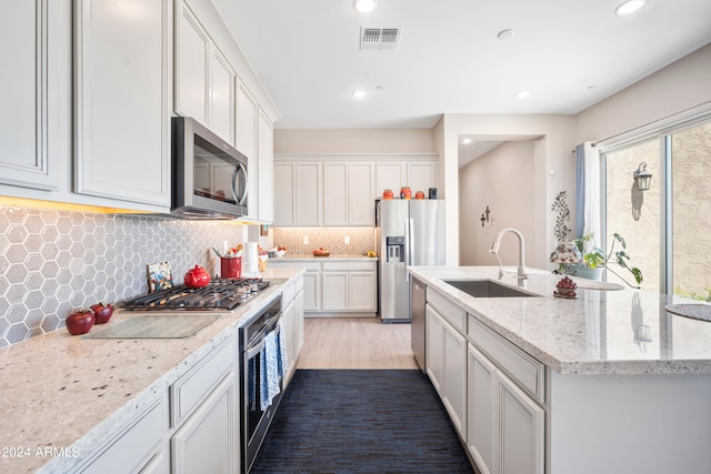 kitchen with appliances with stainless steel finishes, a wealth of natural light, a center island with sink, and sink