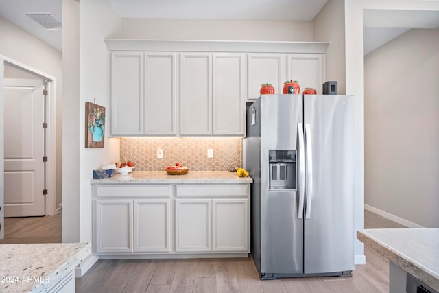 kitchen featuring white cabinets, stainless steel fridge, decorative backsplash, and light hardwood / wood-style flooring