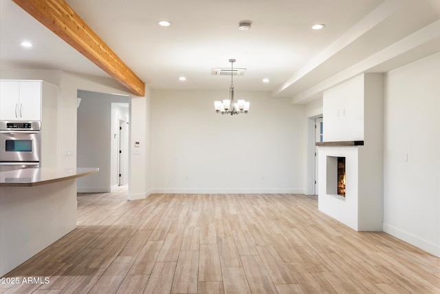1801 E Berridge Ln, Phoenix, AZ 85016 - unfurnished living room with a chandelier, light wood-style flooring, recessed lighting, beamed ceiling, and a lit fireplace