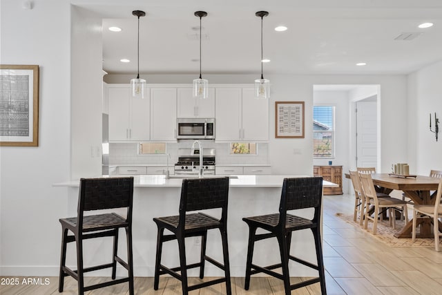 2204 E Kelly Dr, Gilbert, AZ 85298 - kitchen featuring light countertops, a sink, a breakfast bar area, tasteful backsplash, and appliances with stainless steel finishes