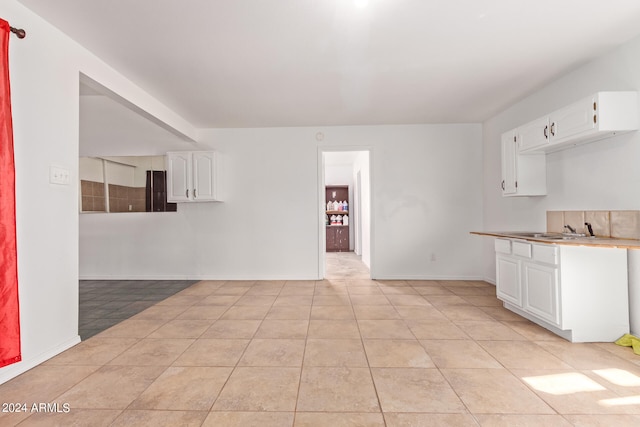 kitchen with white cabinets, sink, and light tile patterned floors