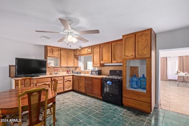 kitchen featuring backsplash, black range with gas cooktop, dark tile patterned floors, and ceiling fan