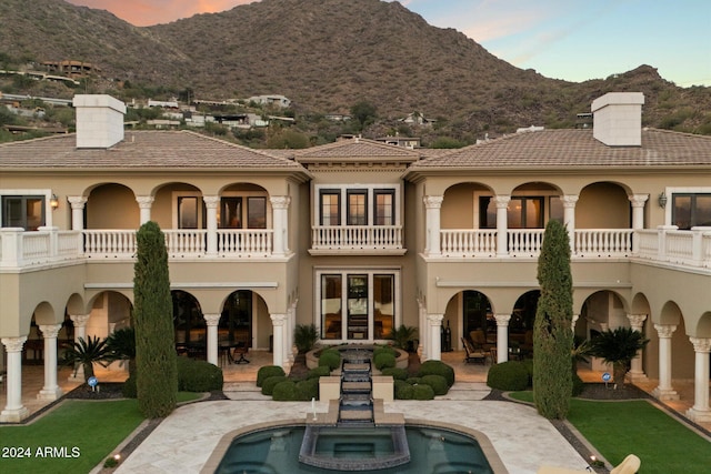 back of property featuring a mountain view, a patio, and a balcony