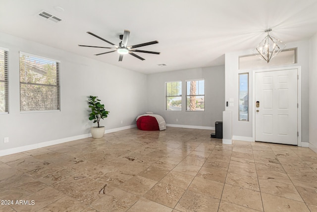 tiled entryway featuring ceiling fan with notable chandelier