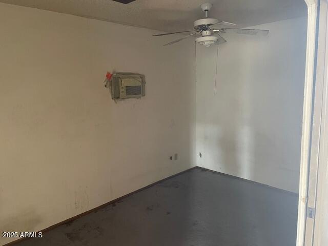 spare room featuring a ceiling fan, a wall mounted AC, and concrete floors