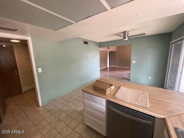 kitchen with stainless steel dishwasher, light countertops, tile patterned flooring, ceiling fan, and a textured ceiling