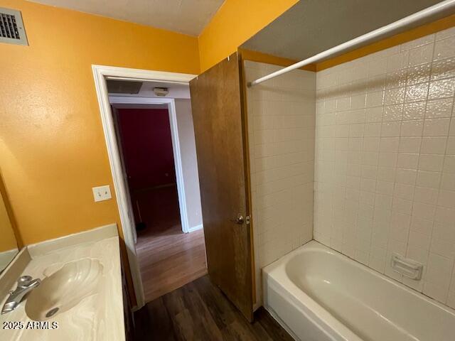 full bath featuring wood finished floors, a sink, and bathing tub / shower combination