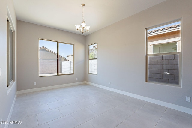 tiled spare room featuring a chandelier