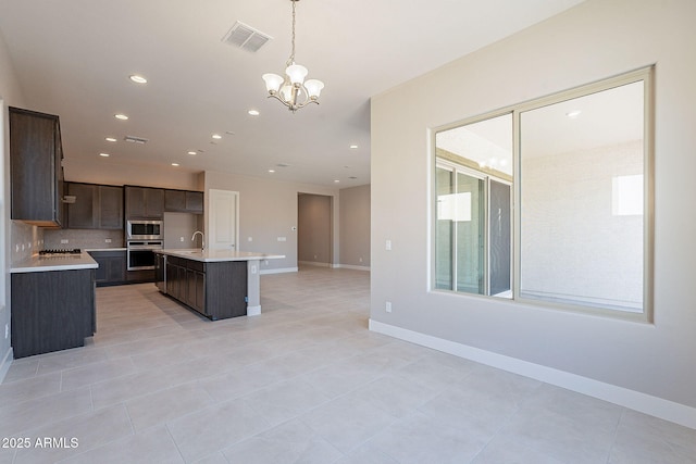 kitchen featuring sink, a kitchen island with sink, hanging light fixtures, an inviting chandelier, and stainless steel appliances