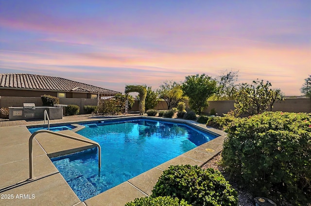 pool at dusk featuring a patio area and area for grilling