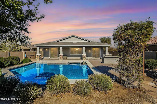 pool at dusk with a patio area