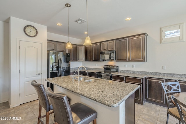 kitchen featuring black appliances, sink, pendant lighting, an island with sink, and light stone counters