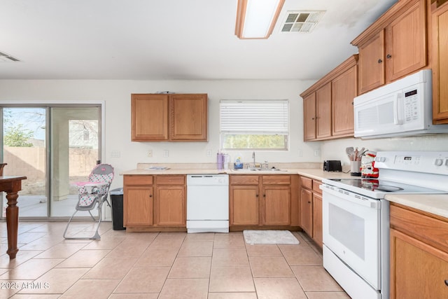 kitchen featuring white appliances, light tile patterned floors, sink, and a wealth of natural light