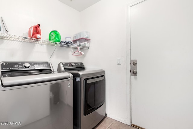 clothes washing area featuring light tile patterned floors and washing machine and clothes dryer