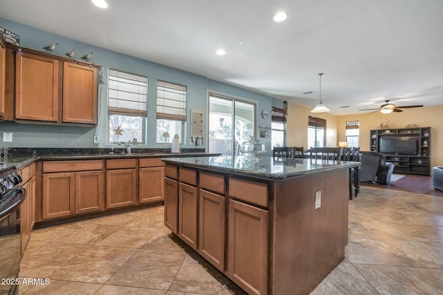 kitchen featuring pendant lighting, sink, dark stone countertops, a kitchen island, and black range