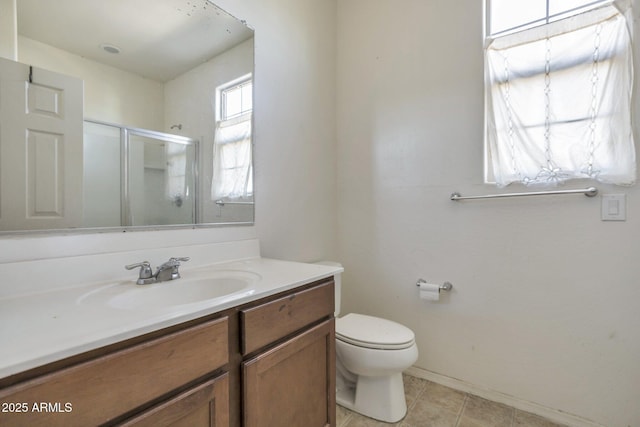 bathroom featuring tile patterned floors, vanity, toilet, and a shower with door