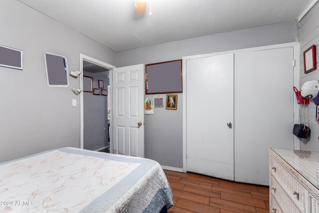 bedroom featuring hardwood / wood-style floors, a textured ceiling, a closet, and ceiling fan