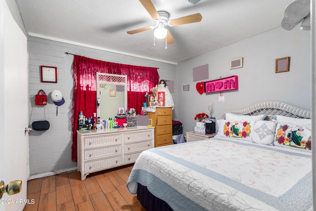 bedroom with light hardwood / wood-style floors, a textured ceiling, and ceiling fan