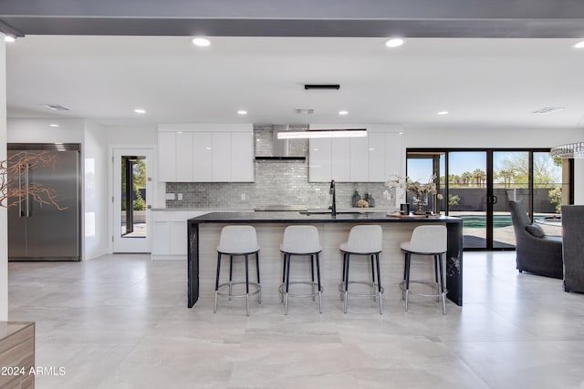 kitchen featuring white cabinetry, a kitchen island with sink, a healthy amount of sunlight, and built in fridge