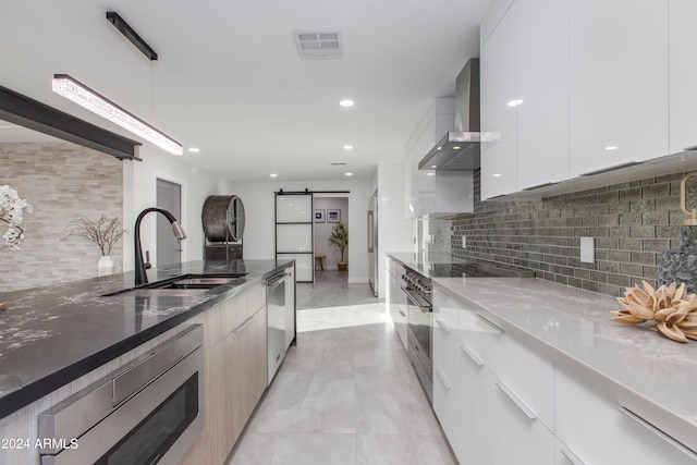 kitchen with wall chimney range hood, sink, tasteful backsplash, dishwasher, and light tile floors