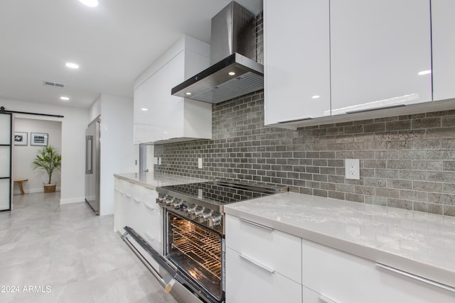 kitchen featuring wall chimney range hood, white cabinets, and stainless steel appliances