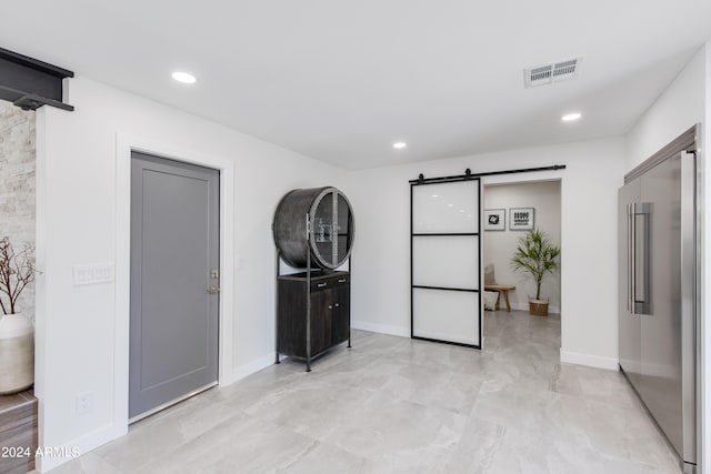 spare room with a barn door and light tile flooring